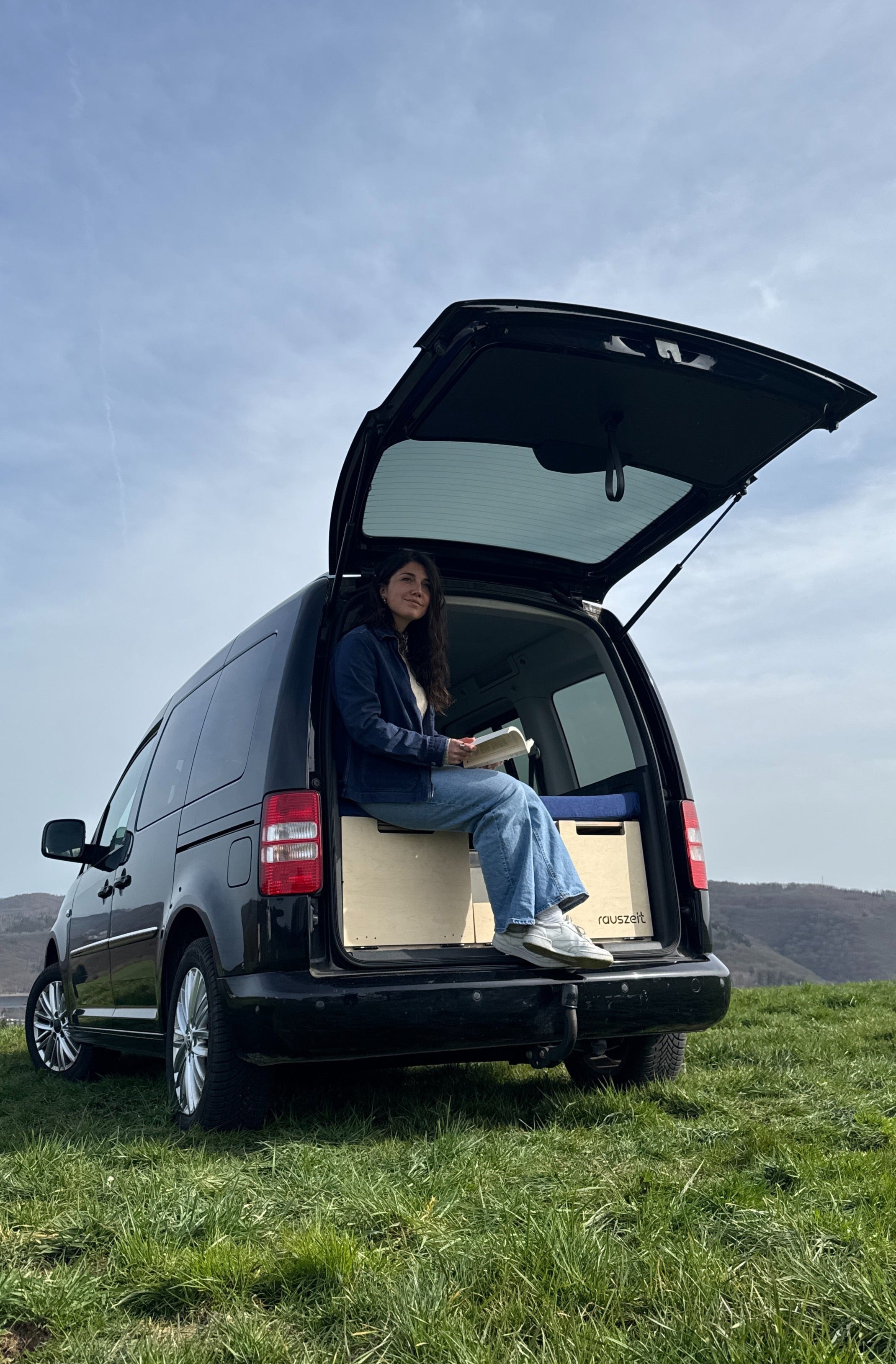 Campingbox für Hochdachkombis Frau sitzt mit Buch im Auto