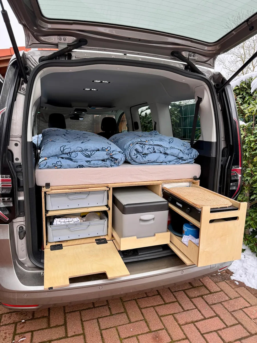 Aufgebaute Campingbox mit Bettzeug, Kühlbox und Gaskocher im Caddy Maxi