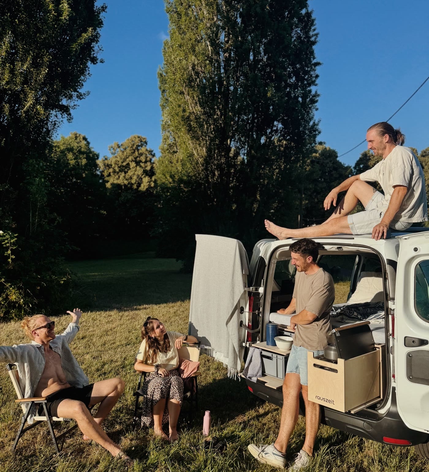 Abends am Camper mit offener Heckklappe und Campingstühlen in der Abendsonne