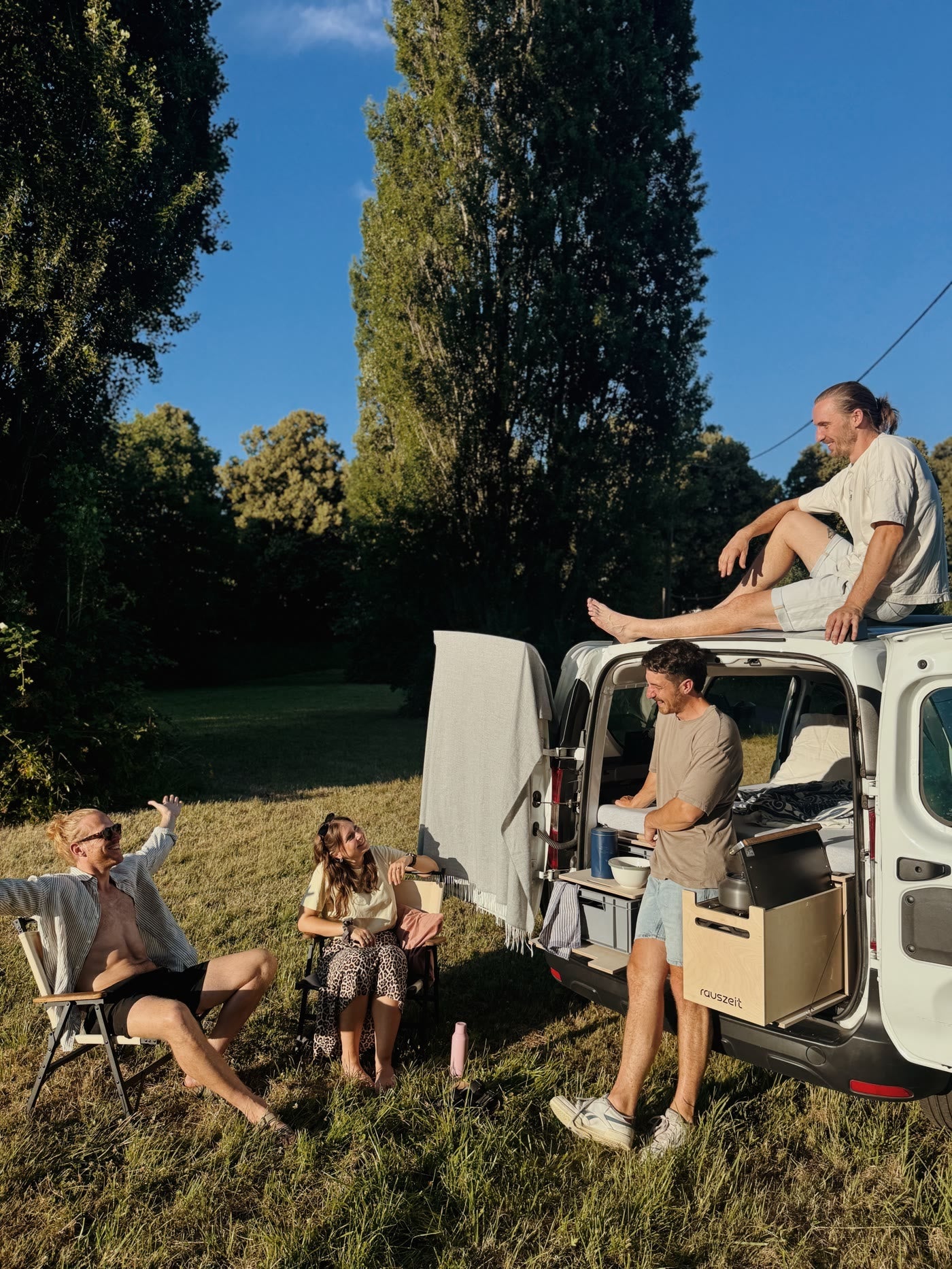 Abends am Camper mit offener Heckklappe und Campingstühlen in der Abendsonne