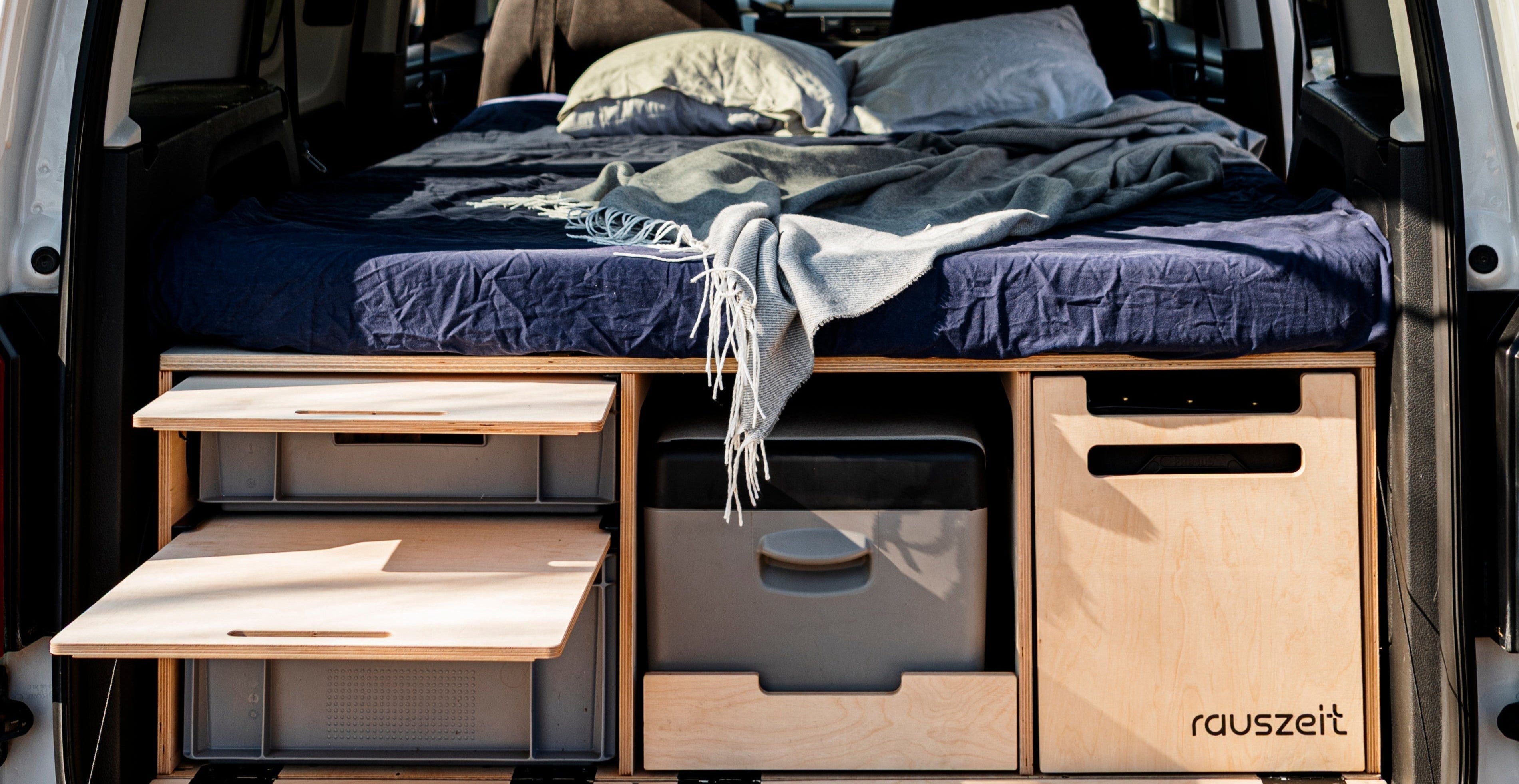 Blick ins Heck mit Bett, Euroboxen und Kühlbox, alles verstaut