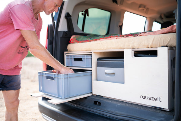 Campingbox mit geöffneten Staufächern und Kochmodul im Kofferraum