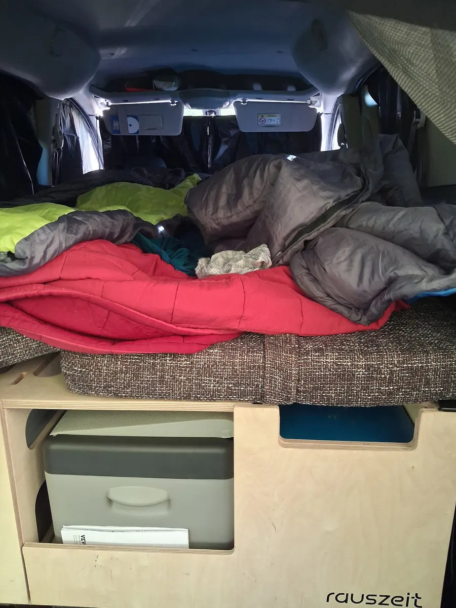 Bezogenes Bett im Hochdachkombi über der Campingbox mit Kühlbox