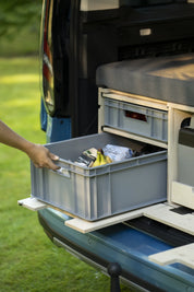Hand zieht die untere Eurobox mit Lebensmitteln aus dem Schubfach der Campingbox
