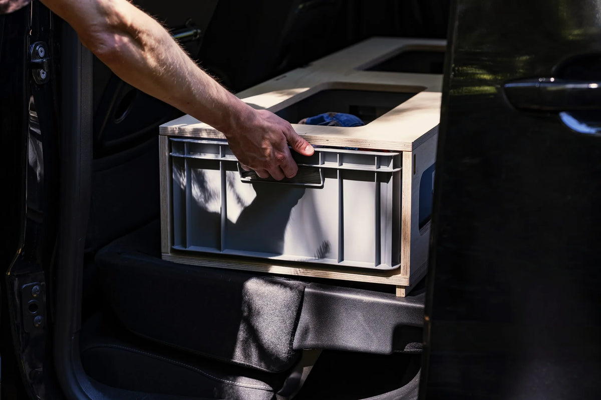 Hand zieht eine Eurobox aus der niedrigen Zusatzbox im Fiat Doblò, Blick durch die Schiebetür