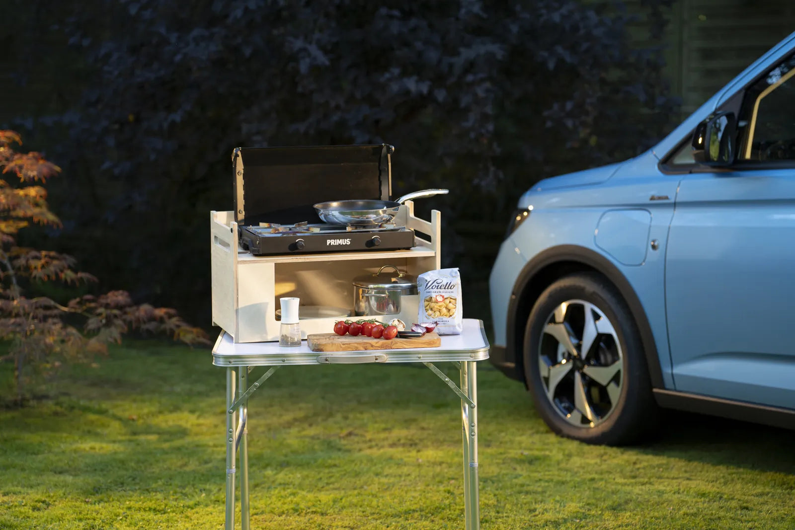 Herausgenommenes Kochmodul der Rauszeit Campingbox auf einem Campingtisch neben einem Ford Tourneo Connect