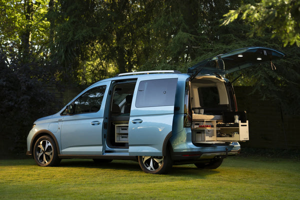 Hellblauer Ford Tourneo Connect mit offener Schiebetür und Heckklappe, darin die Rauszeit Campingbox mit Kochmodul
