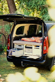 Campingbox im Hochdachkombi mit Bett, Euroboxen und Kühlbox, Heckansicht im Abendlicht