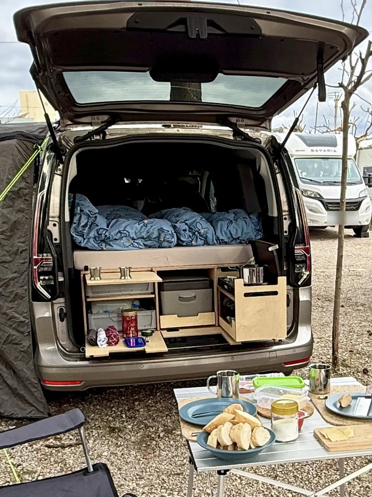 Frühstück am Heck des VW Caddy Maxi mit geöffneter Küche der Campingbox