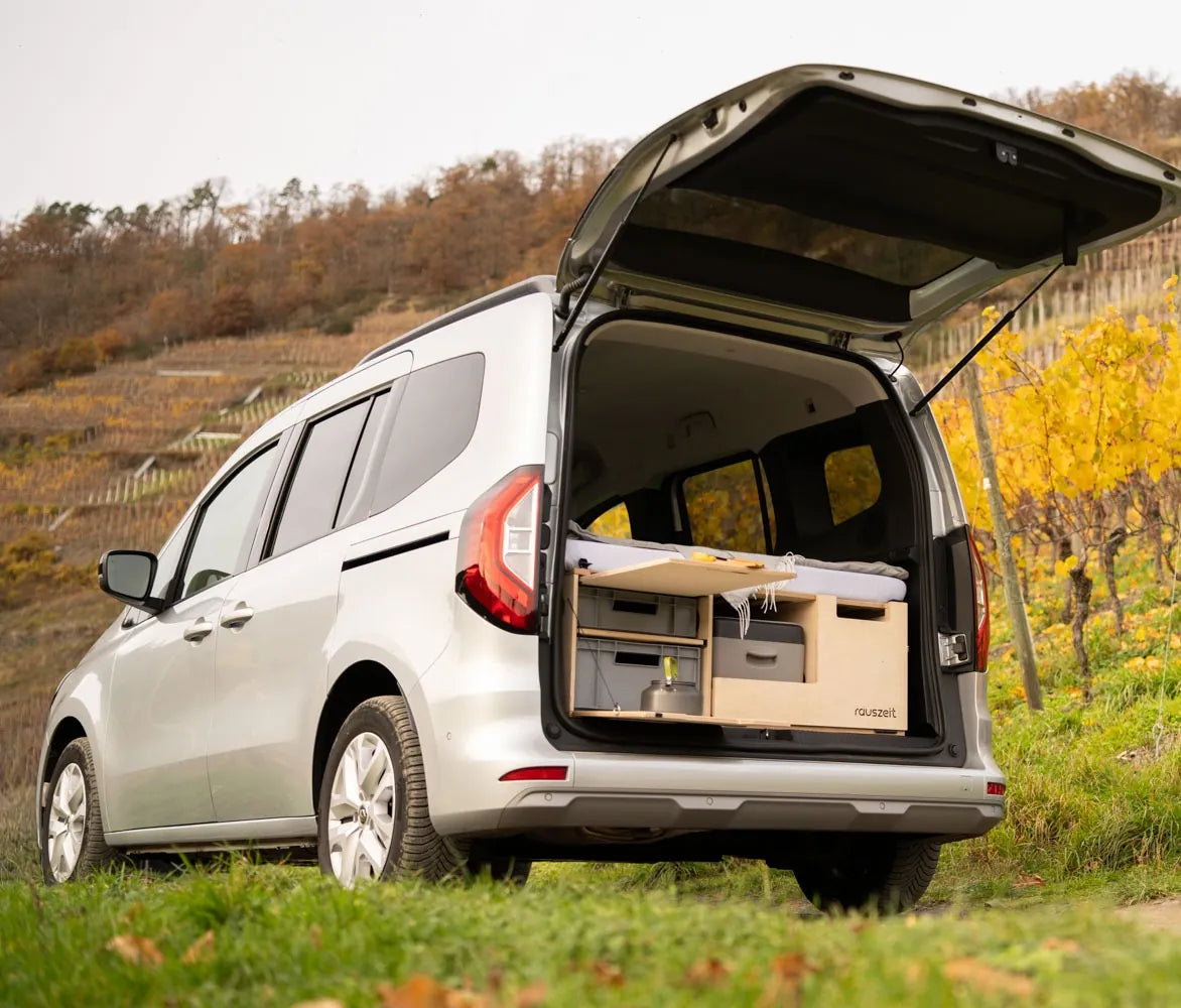 Campingbox mit geöffneter Heckklappe zwischen herbstlichen Weinbergen