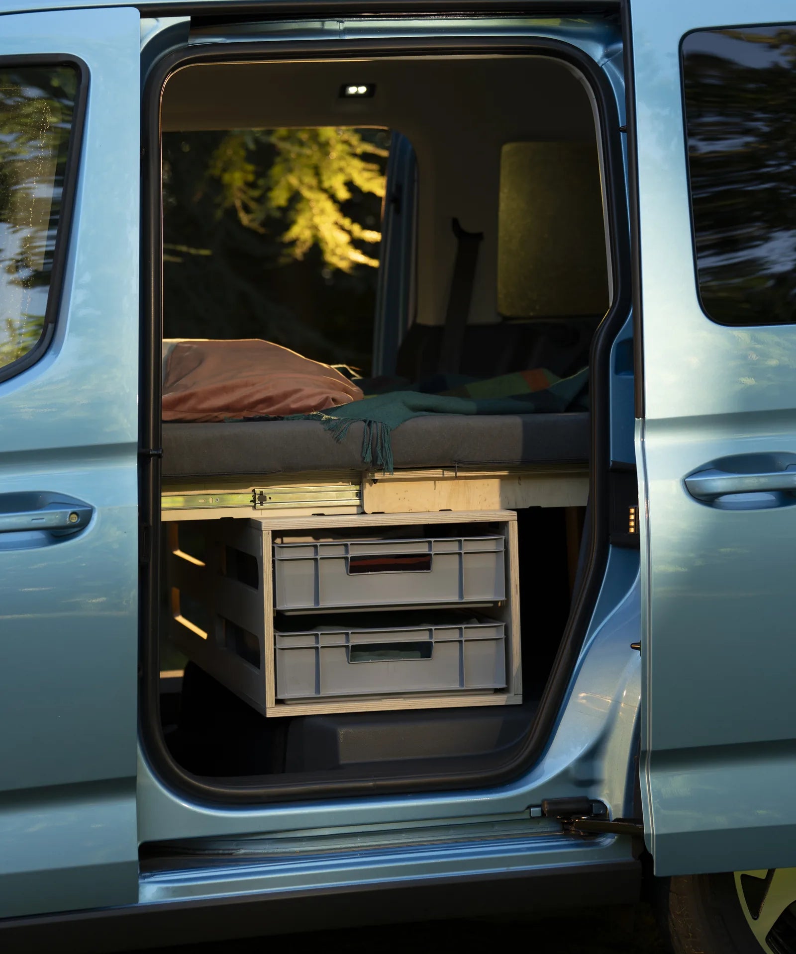 Offene Schiebetür eines Ford Tourneo Connect, dahinter die Rauszeit Zusatzbox mit zwei Euroboxen unter dem Bett